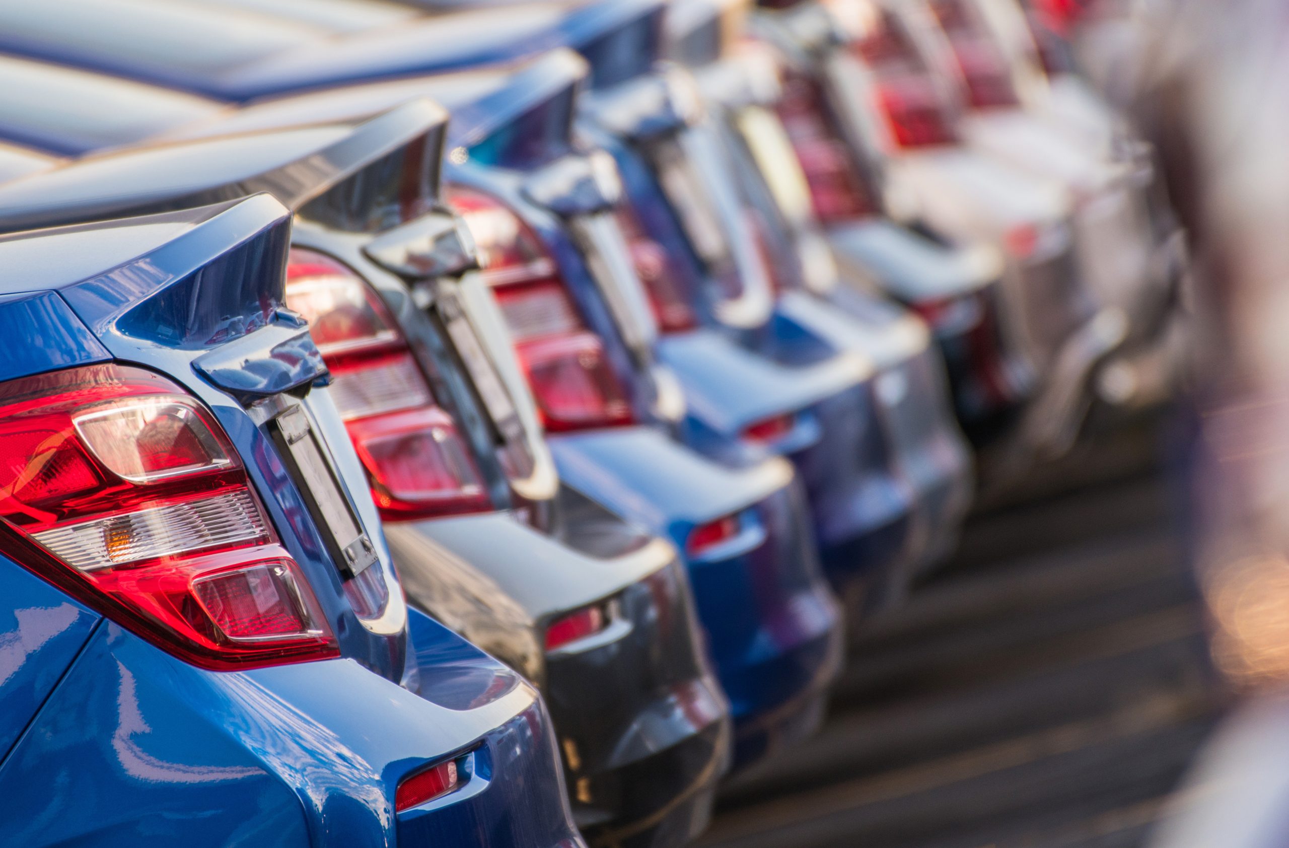 A diagonal row of blue cars focusing on their taillights.