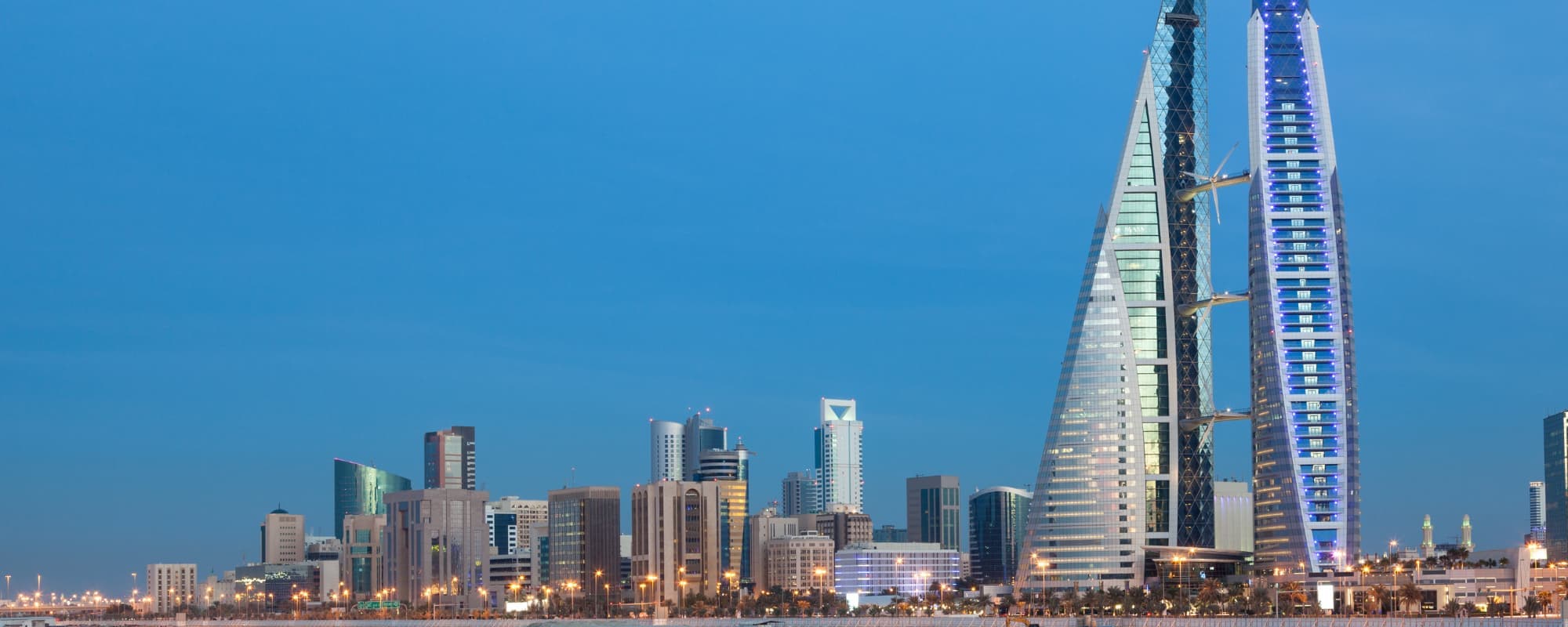 Dusk cityscape with modern skyscrapers and streetlights.