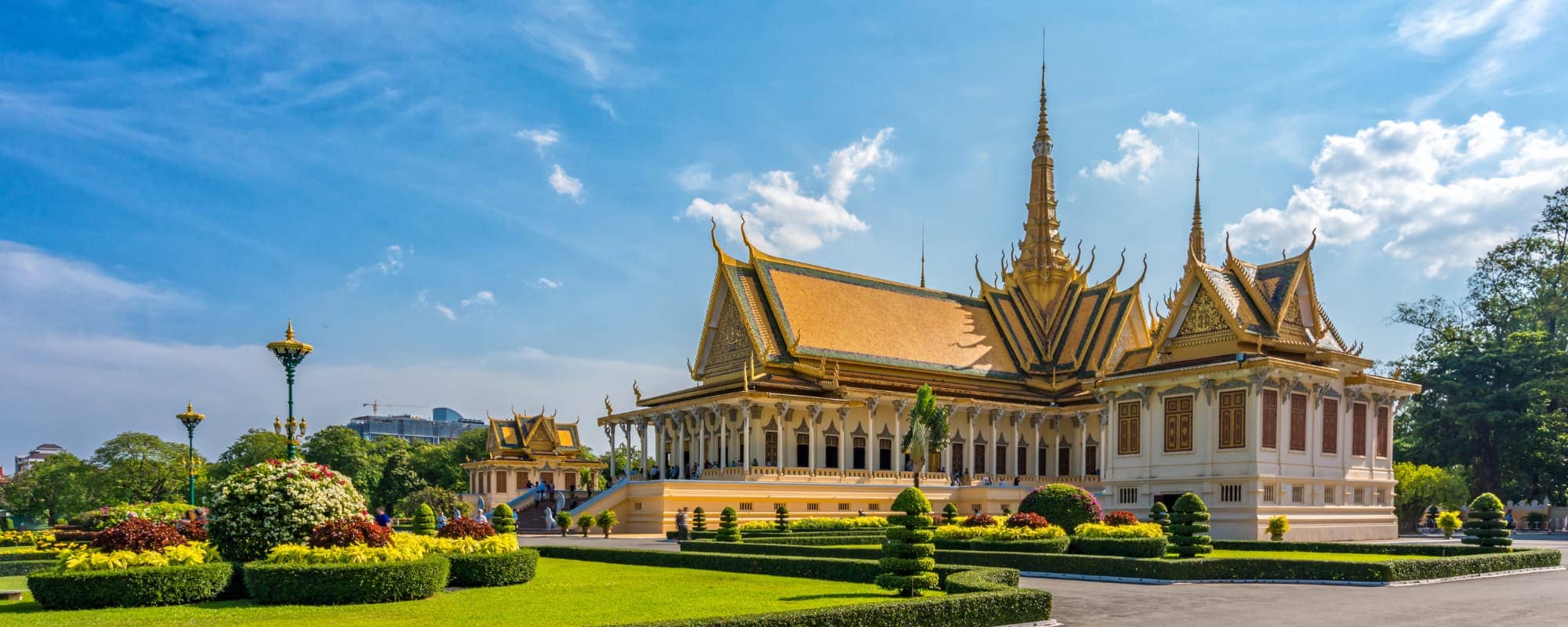 Ornate temple-like building with gold-tiered roofs and a manicured garden in the foreground.
