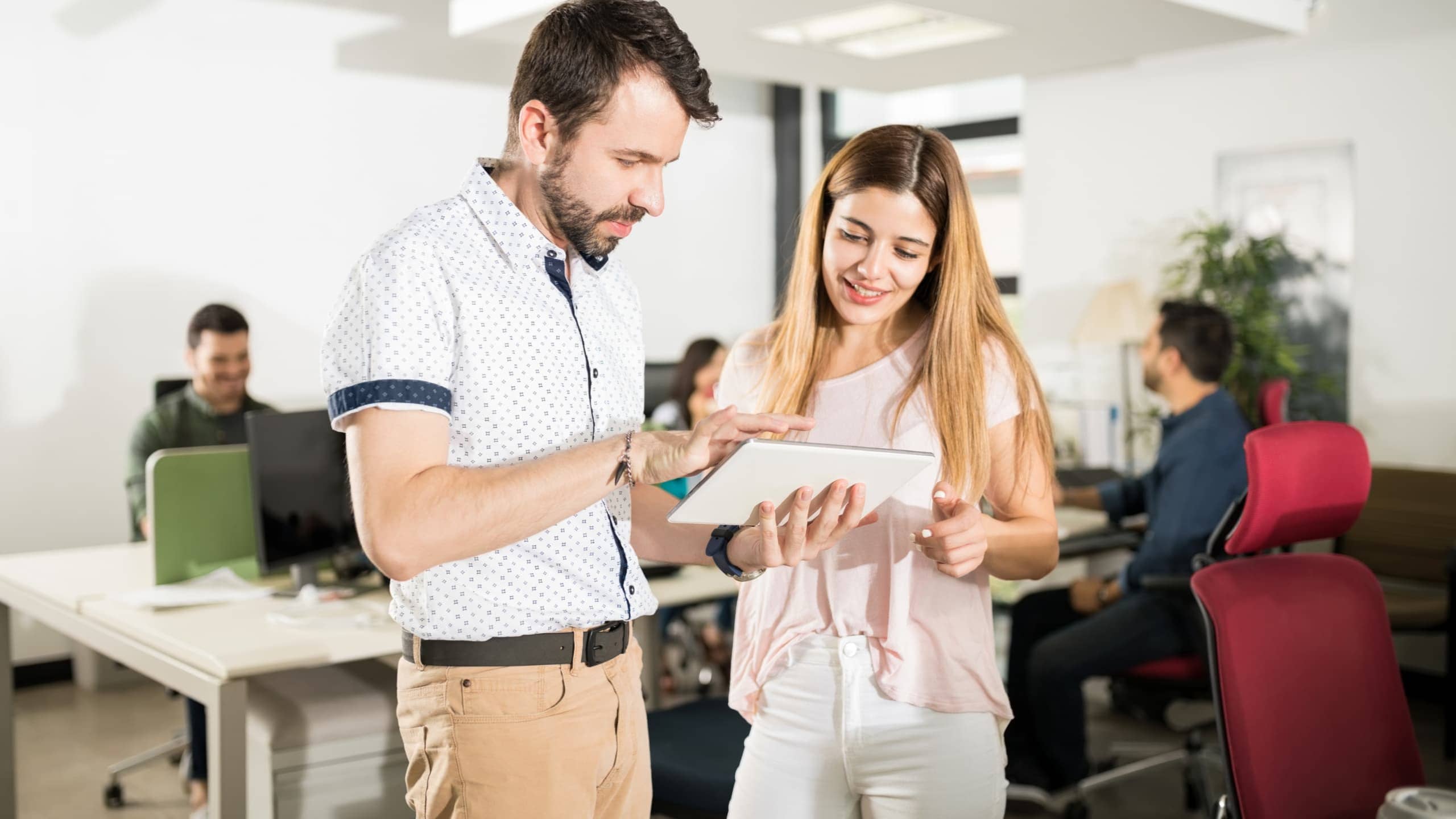 Two people in an office looking at a tablet together.