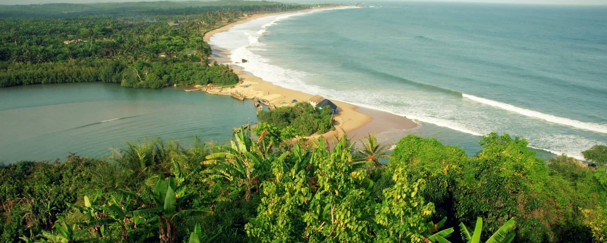 A tropical coastline with lush greenery, a sandbar, a lagoon, and an expansive ocean view.