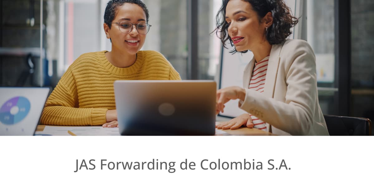 Two people working together at a table with a laptop in an office.